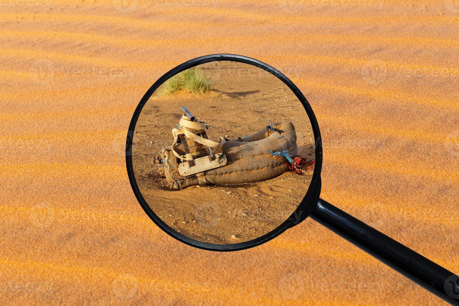 saddle for camel on the sand, view through a magnifying glass against the background of sand photo