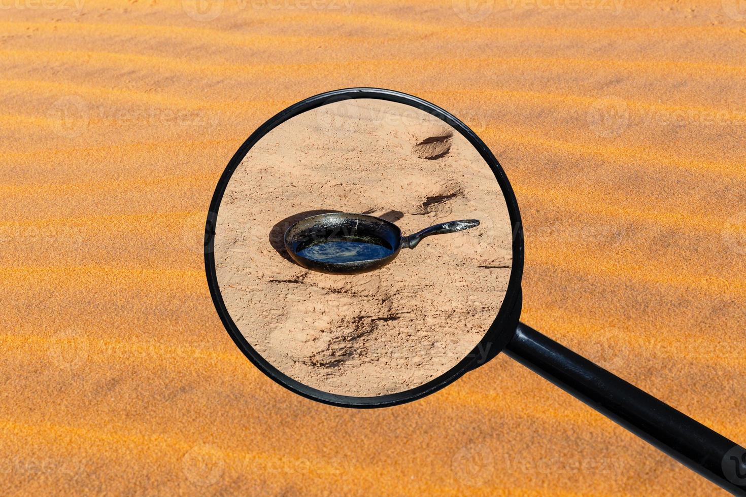 pan stands on sand in Sahara desert, view through a magnifying glass against the background of sand photo