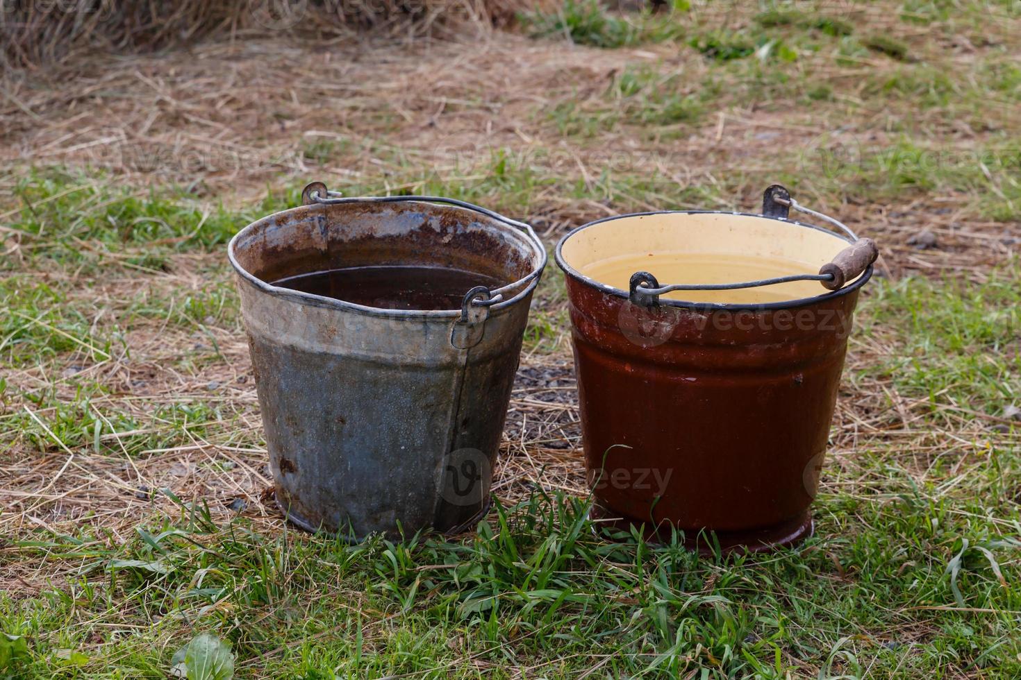 two old iron buckets stand on the ground photo