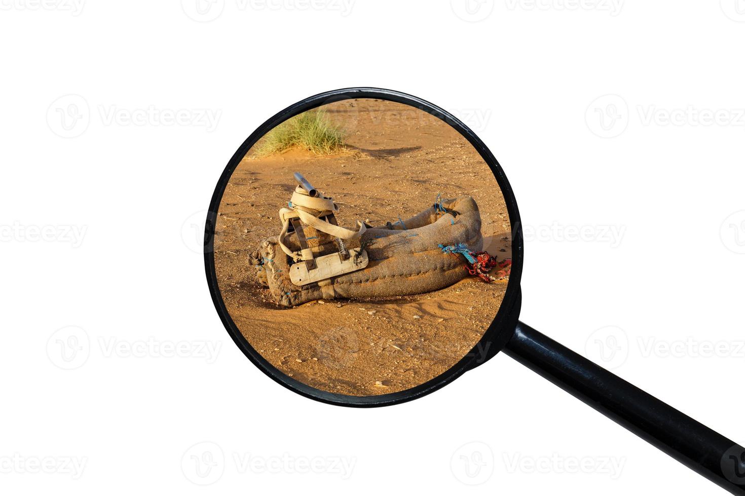 saddle for camel on the sand, view through a magnifying glass on a white background photo