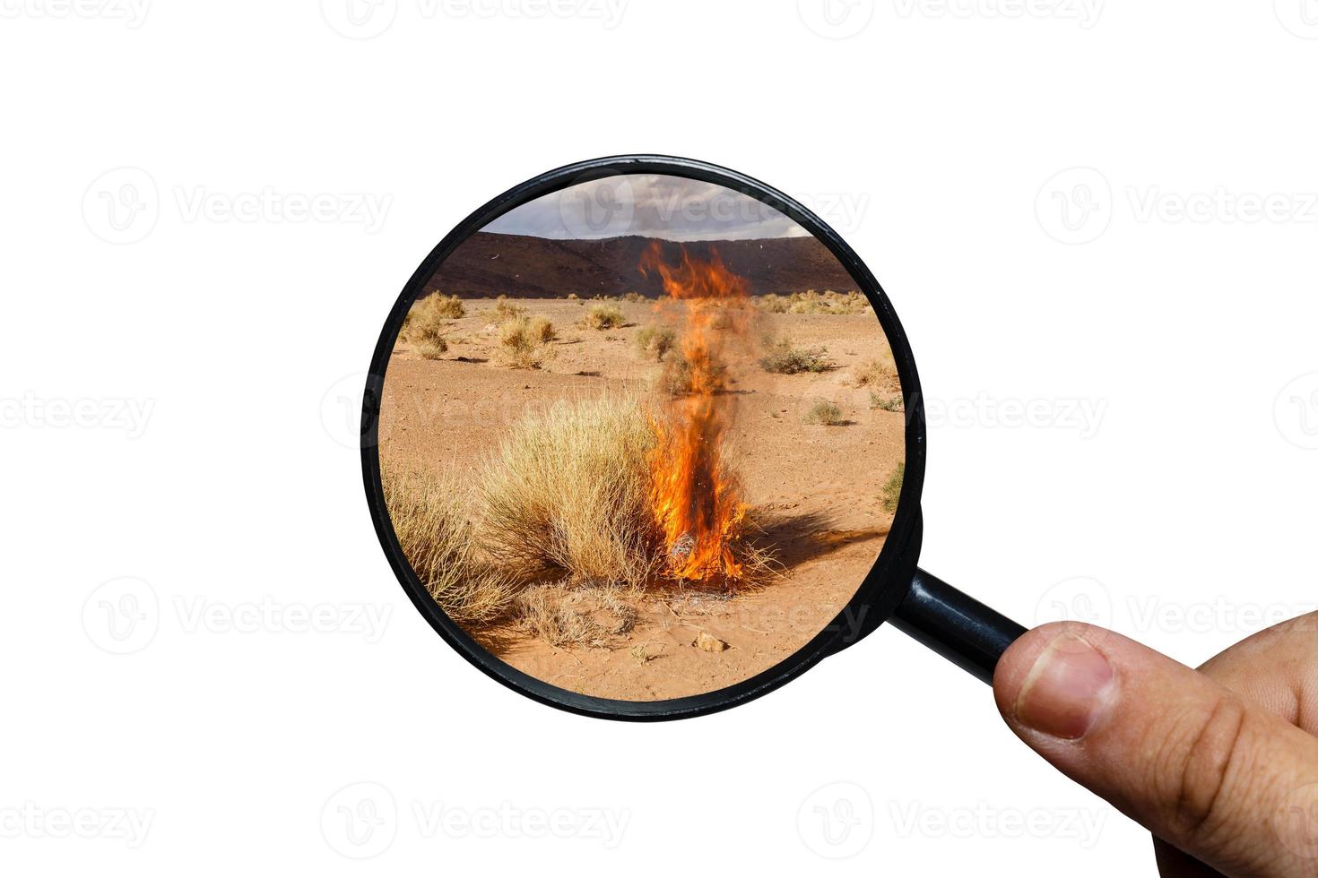 dry burning grass in the Sahara desert, view through a magnifying glass on a white background, magnifying glass in hand. photo