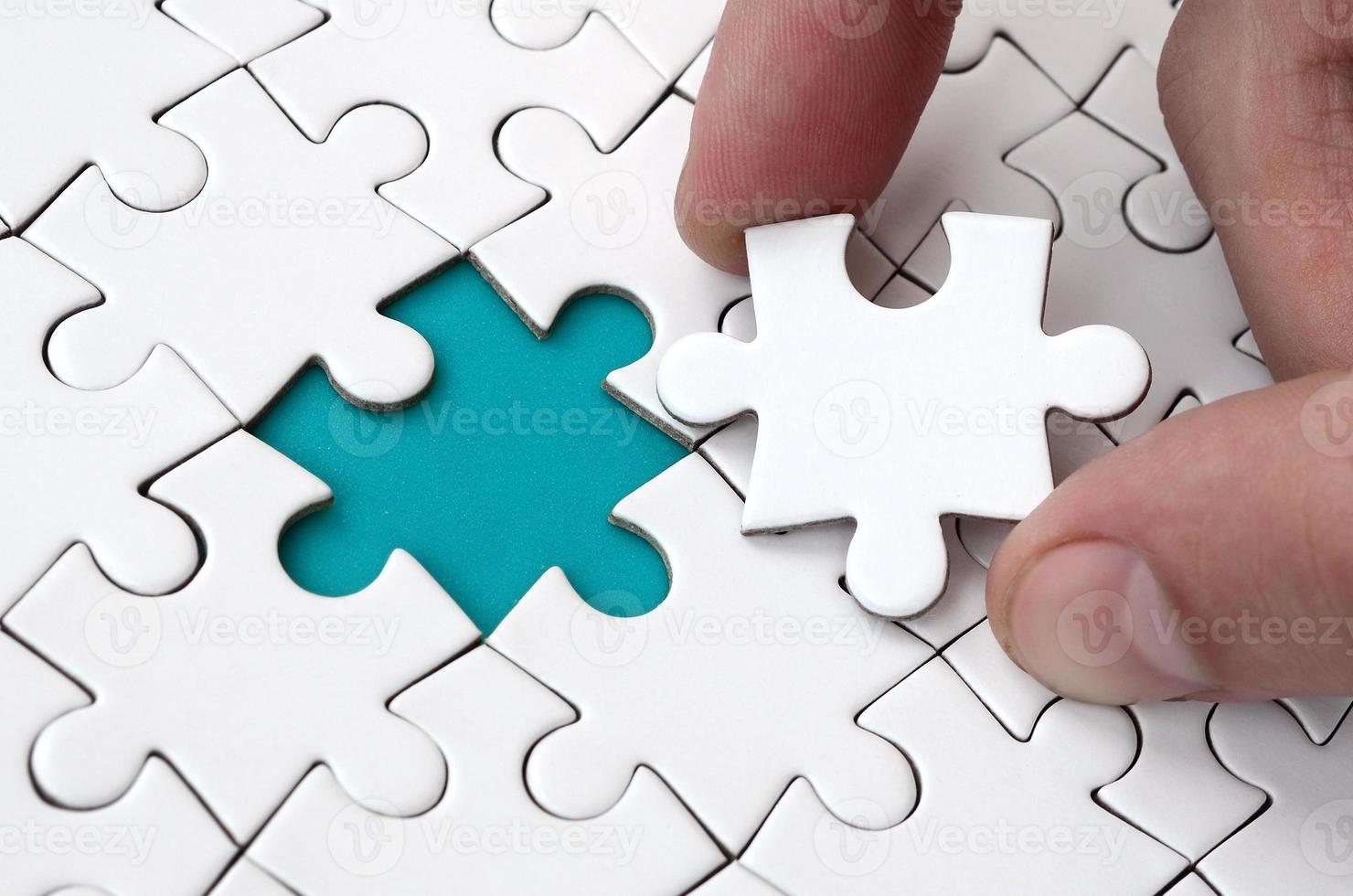 The human hand fills the last missing elements of the surface from the jigsaw puzzle. The concept of the completion of the initiated cases photo