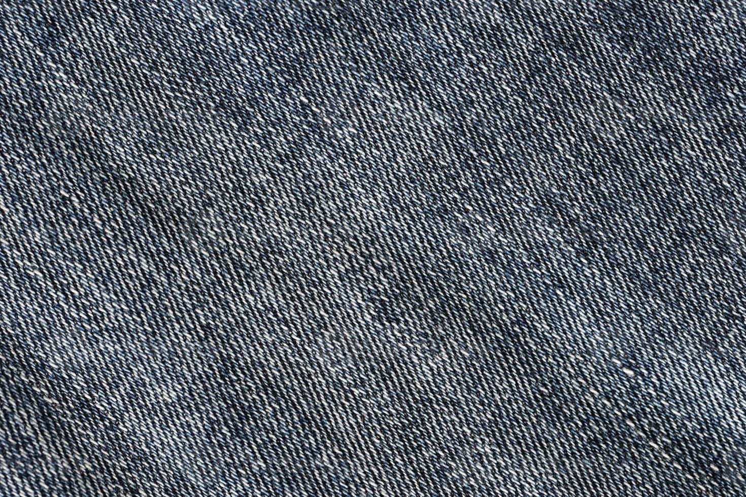 Detailed abstract texture of dark blue denim cloth. Background image of old used denim trousers fabric photo