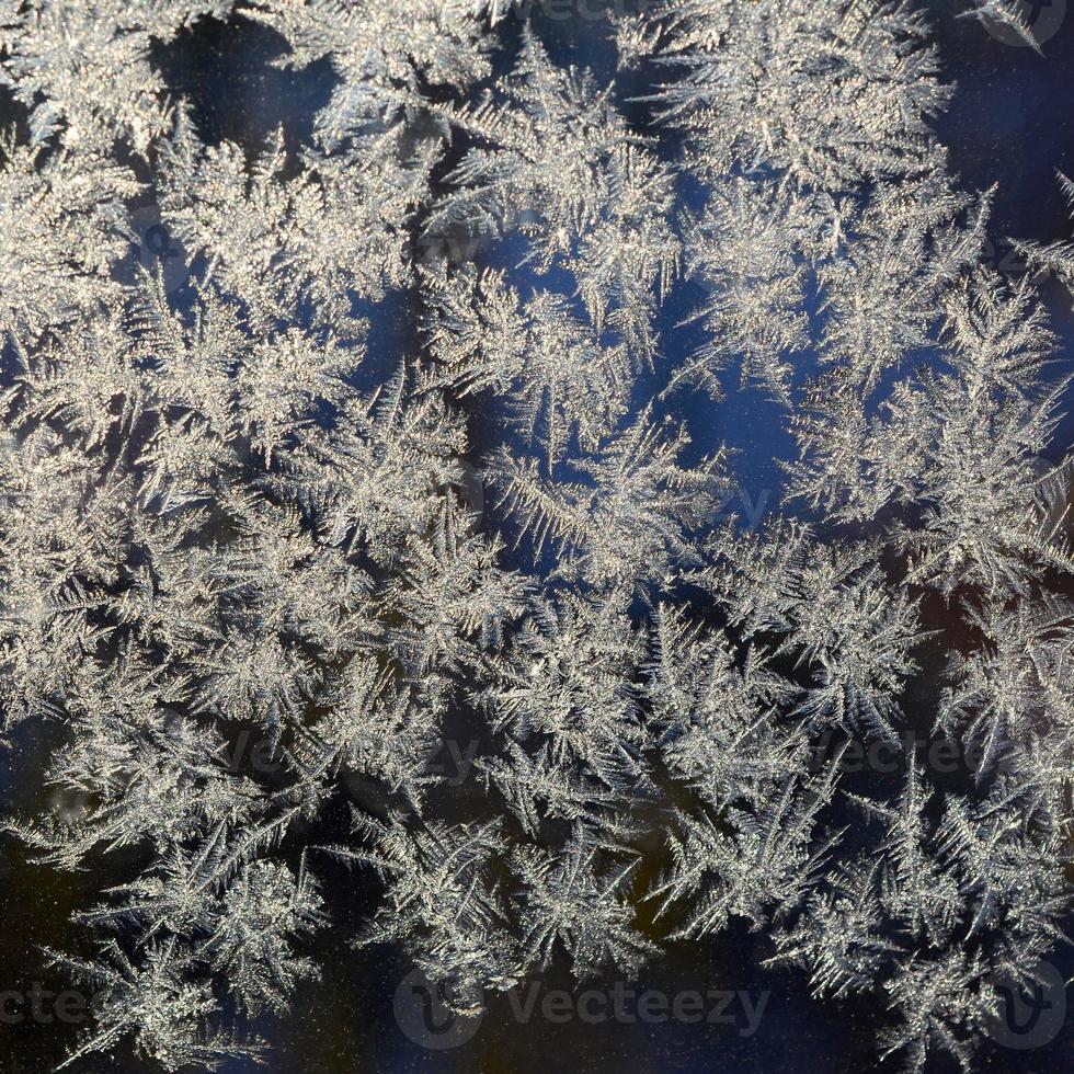 Snowflakes frost rime macro on window glass pane photo