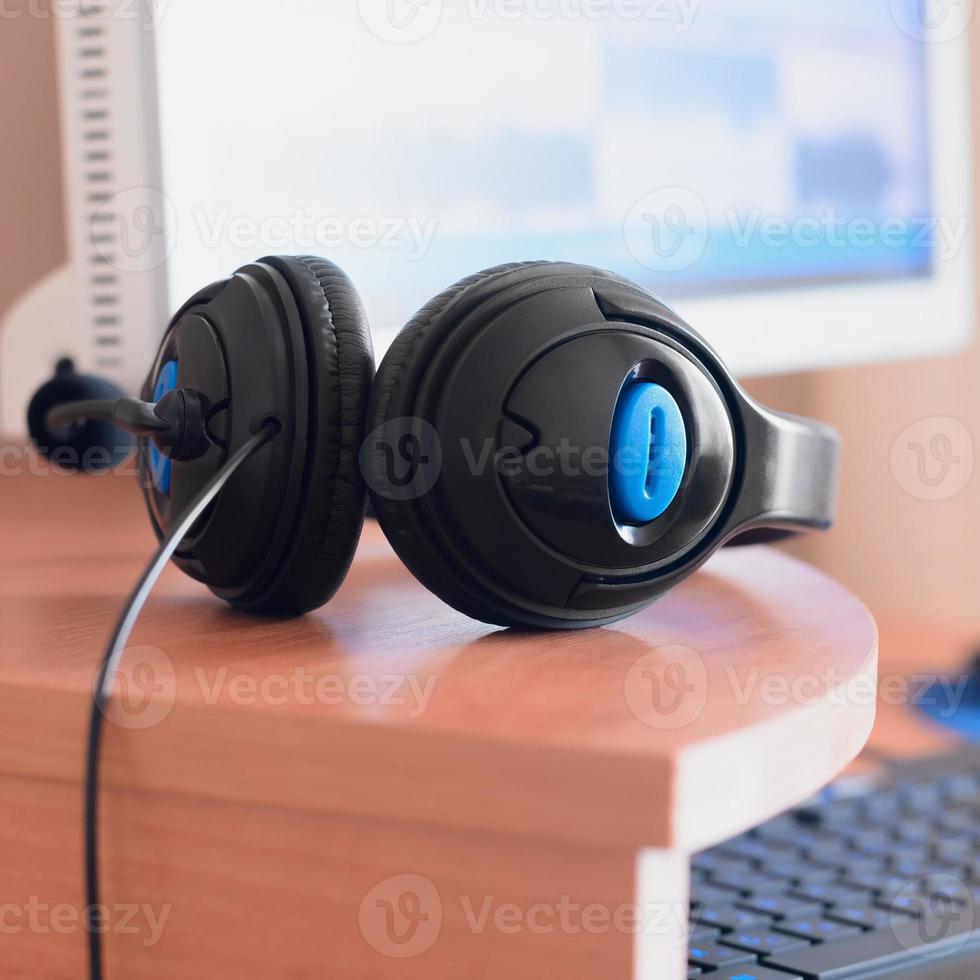 Big black headphones lie on the wooden desktop of the sound designer photo