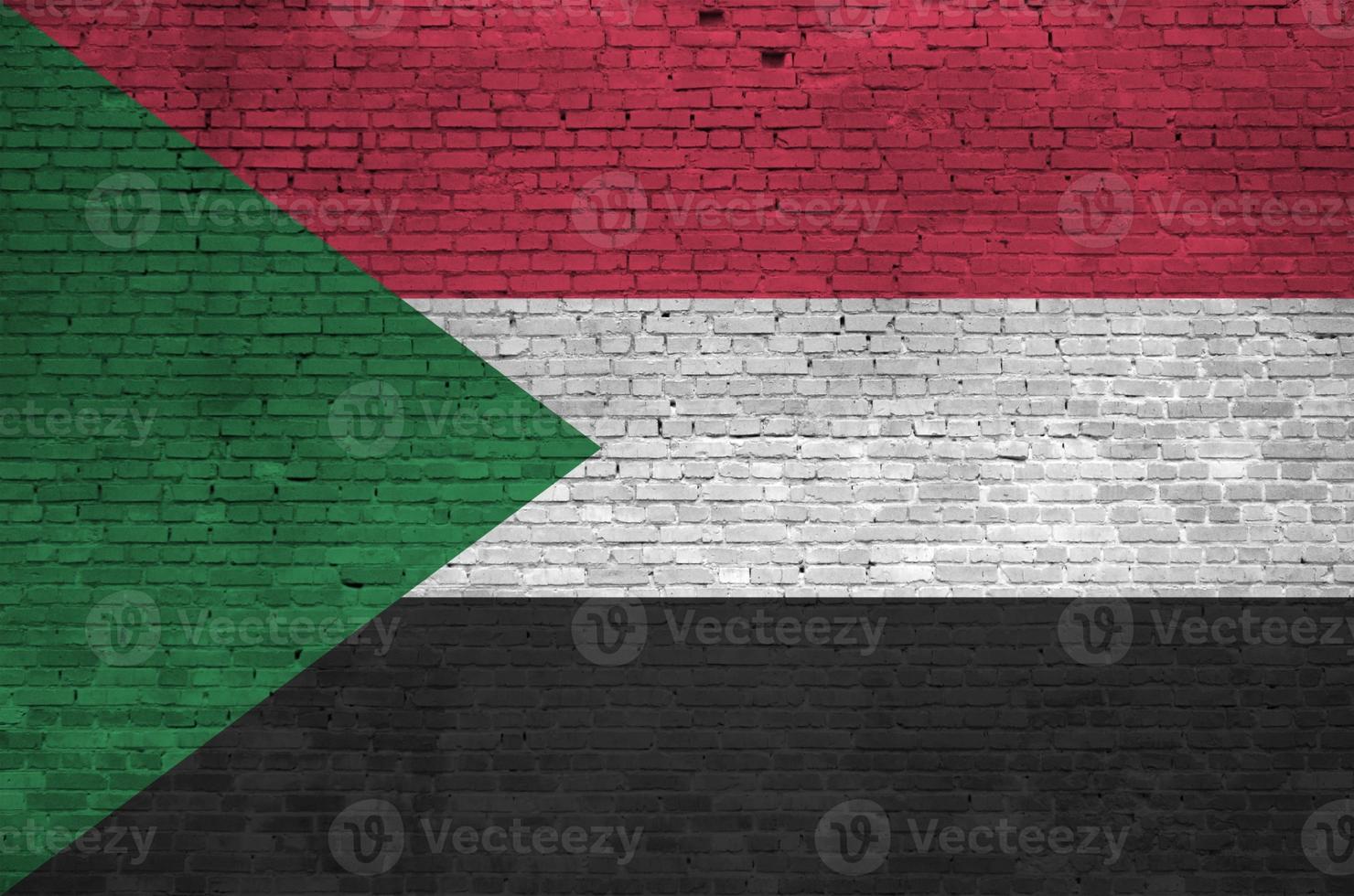 Sudan flag depicted in paint colors on old brick wall. Textured banner on big brick wall masonry background photo