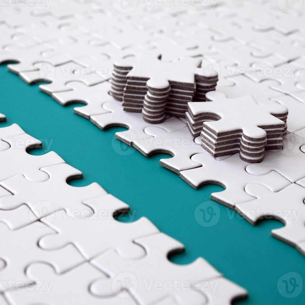 The blue path is laid on the platform of a white folded jigsaw puzzle. The missing elements of the puzzle are stacked nearby. Texture image with space for text photo