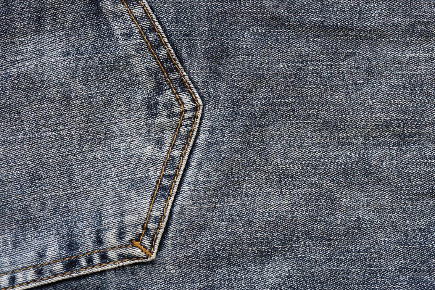 Detailed abstract texture of dark blue denim cloth. Background image of old used denim trousers fabric photo