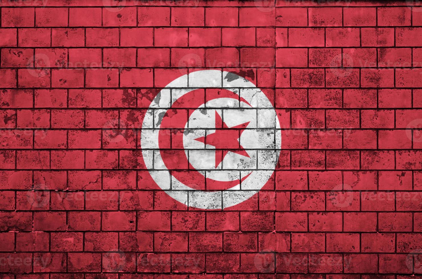 La bandera de Túnez está pintada en una vieja pared de ladrillos. foto