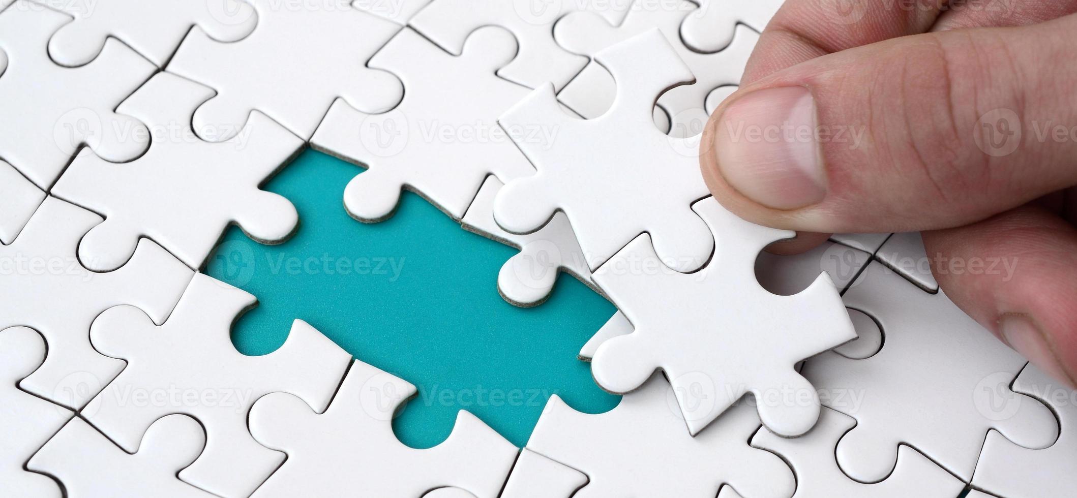 The human hand fills the last missing elements of the surface from the jigsaw puzzle. The concept of the completion of the initiated cases photo