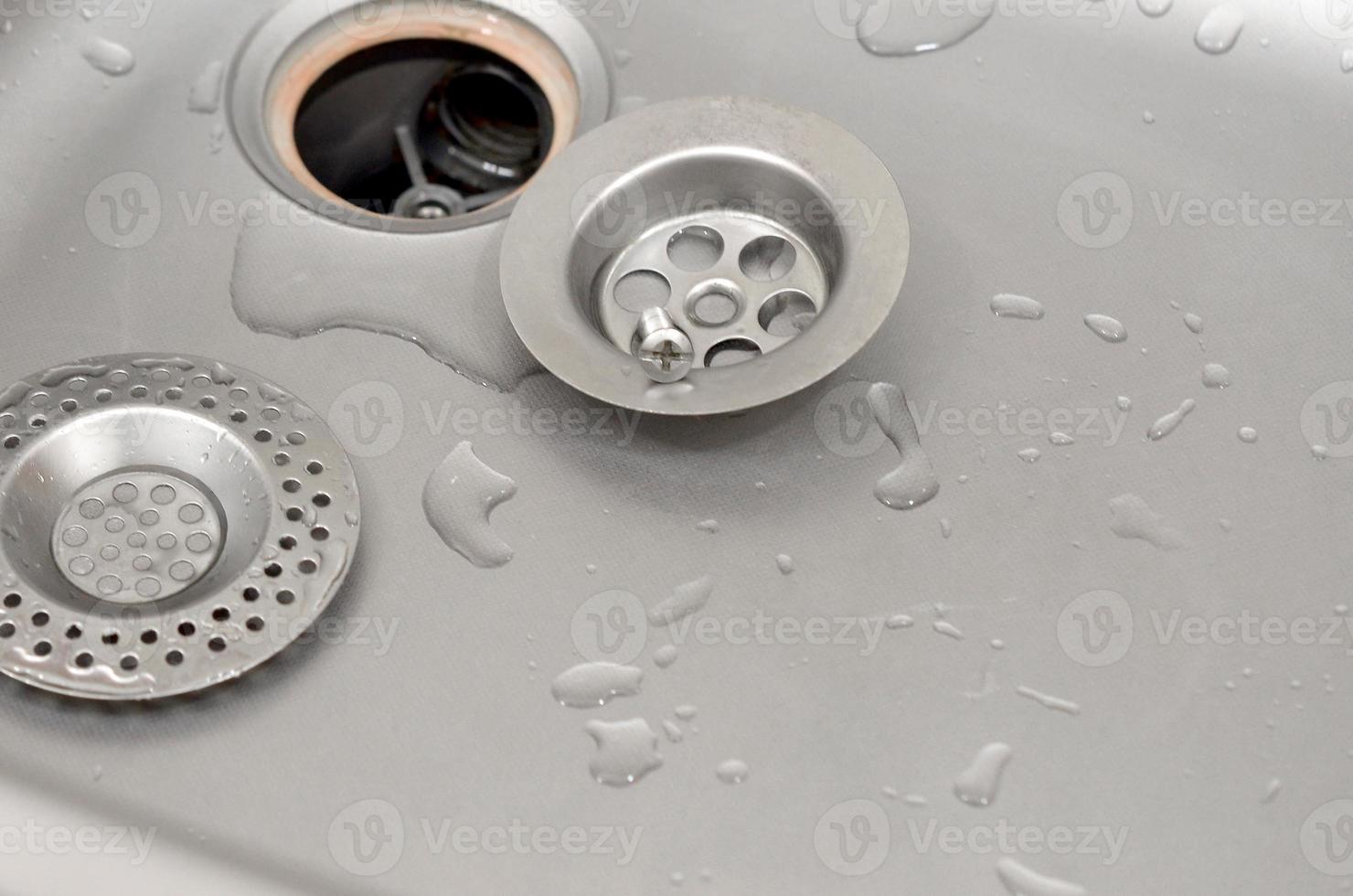 Silvery kitchen sink with a disassembled protective filter during the repair process photo