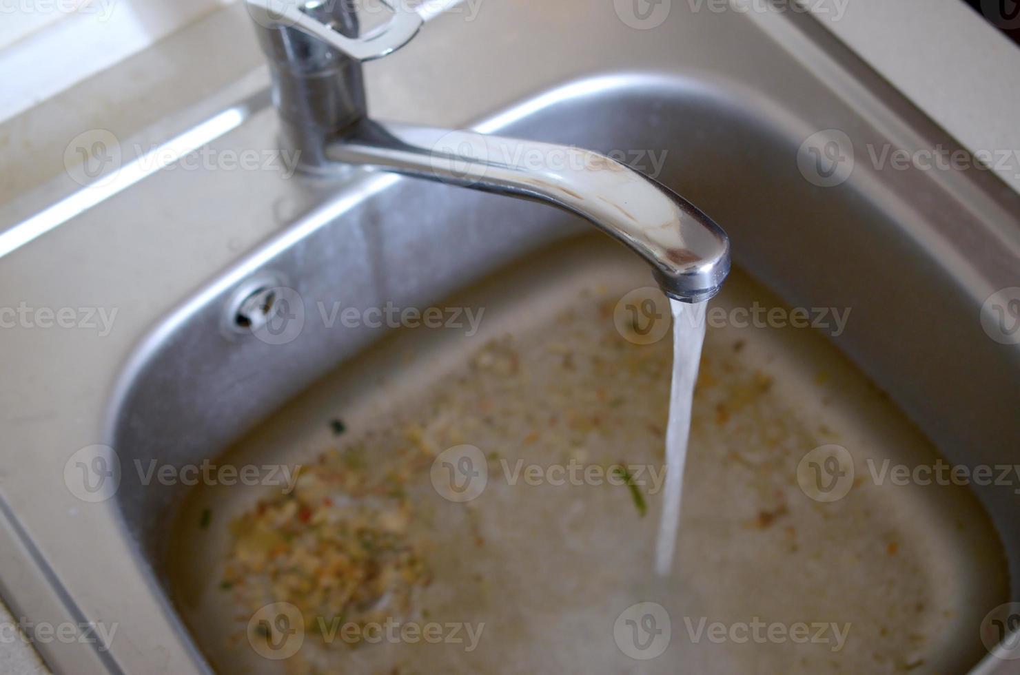 Stainless steel sink plug hole close up full of water and particles of food photo