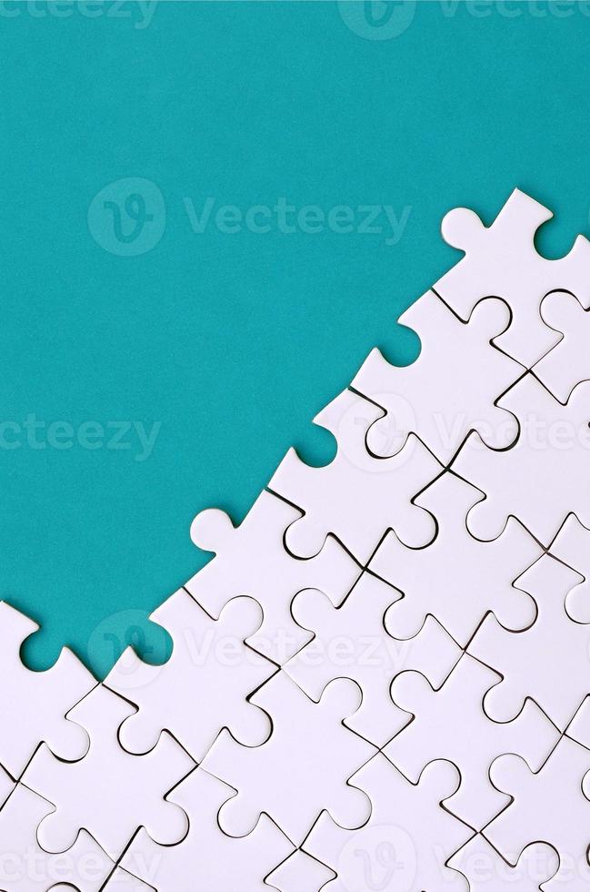 Fragment of a folded white jigsaw puzzle on the background of a blue plastic surface. Texture photo with copy space for text