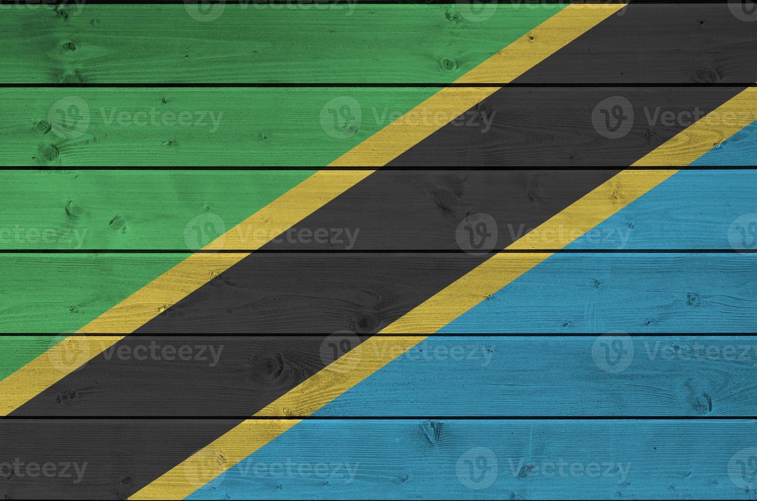 Tanzania flag depicted in bright paint colors on old wooden wall. Textured banner on rough background photo