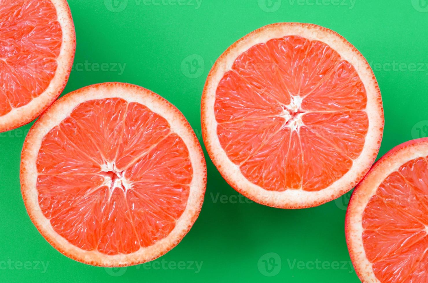 Top view of a several grapefruit slices on bright background in green
