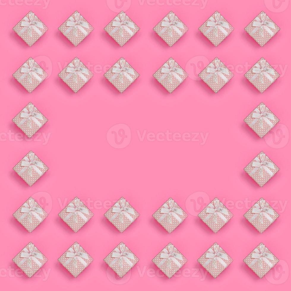 Frame of pink gift boxes lies on texture background of fashion pastel pink color paper in minimal concept. Abstract trendy pattern photo