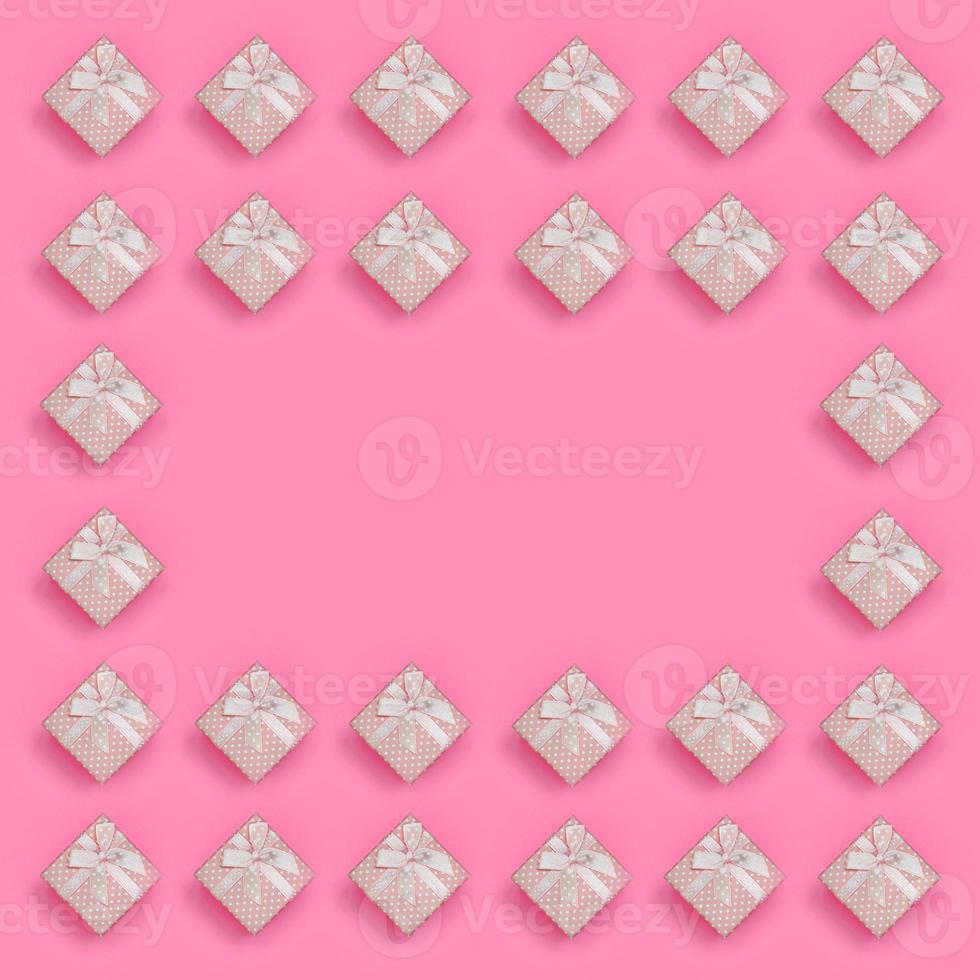 Frame of pink gift boxes lies on texture background of fashion pastel pink color paper in minimal concept. Abstract trendy pattern photo