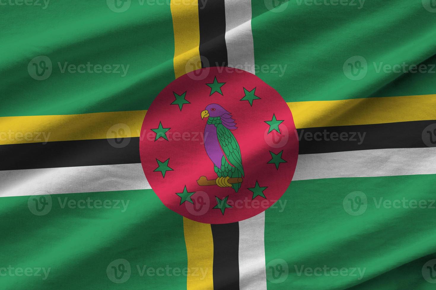 Dominica flag with big folds waving close up under the studio light indoors. The official symbols and colors in banner photo
