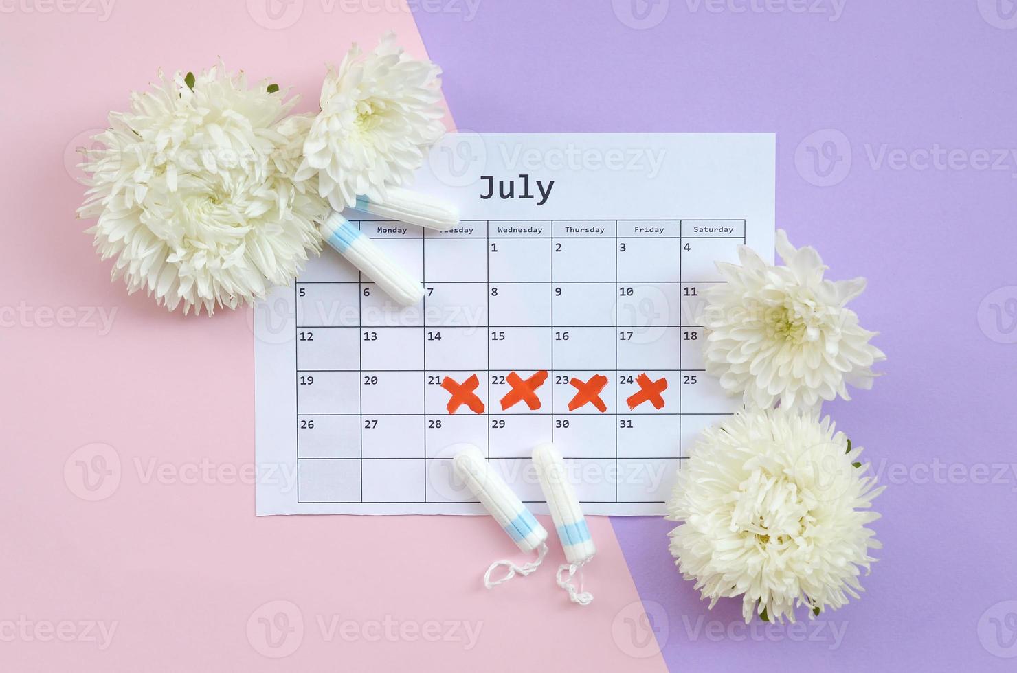 Menstrual tampons on menstruation period calendar with white flowers on lilac and pink background photo