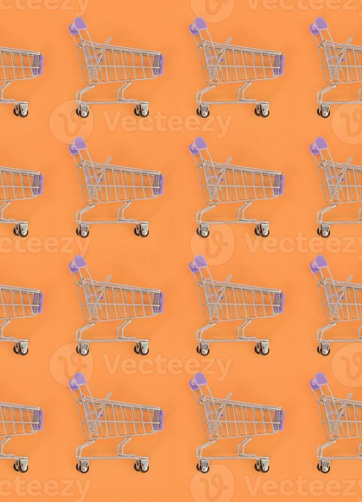 Shopping addiction, shopping lover or shopaholic concept. Many small empty shopping carts perform a pattern on a pastel colored paper background. Flat lay composition, top view photo