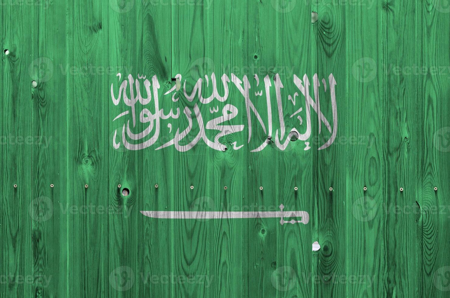 Saudi Arabia flag depicted in bright paint colors on old wooden wall. Textured banner on rough background photo