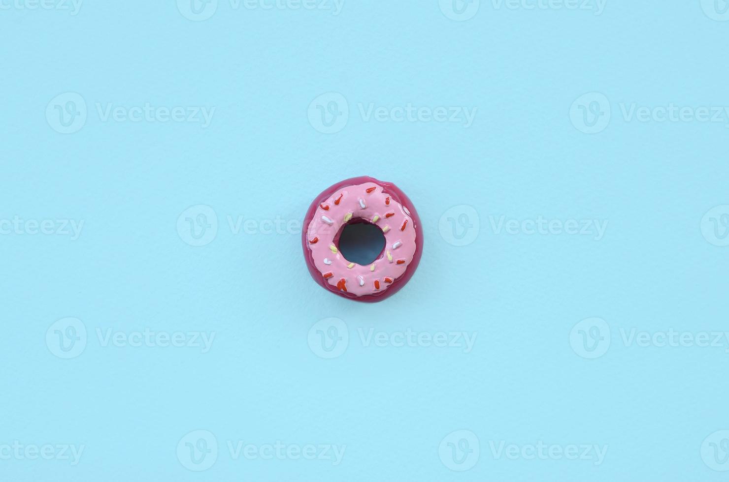 Single small plastic donut lies on a pastel colorful background. Flat lay minimal composition. Top view. photo