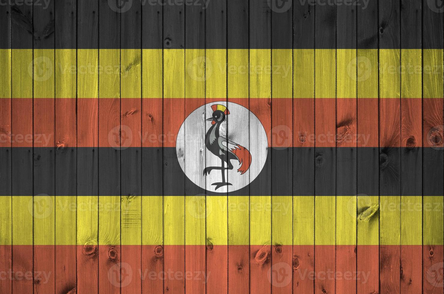 Uganda flag depicted in bright paint colors on old wooden wall. Textured banner on rough background photo