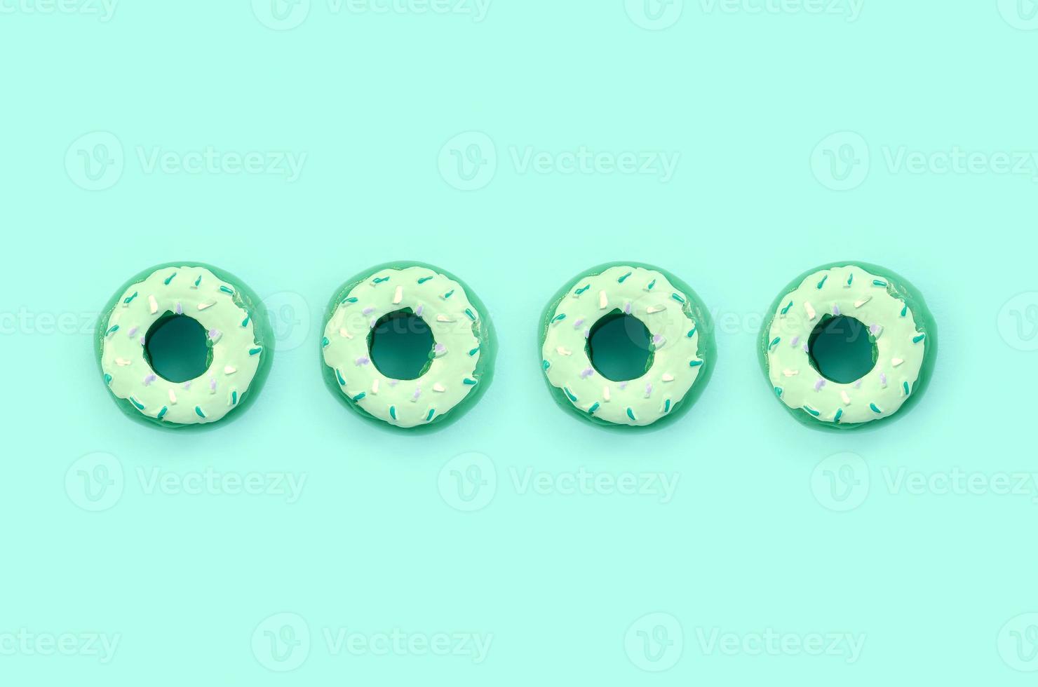 Many small plastic donuts lies on a pastel colorful background. Flat lay minimal pattern. Top view photo