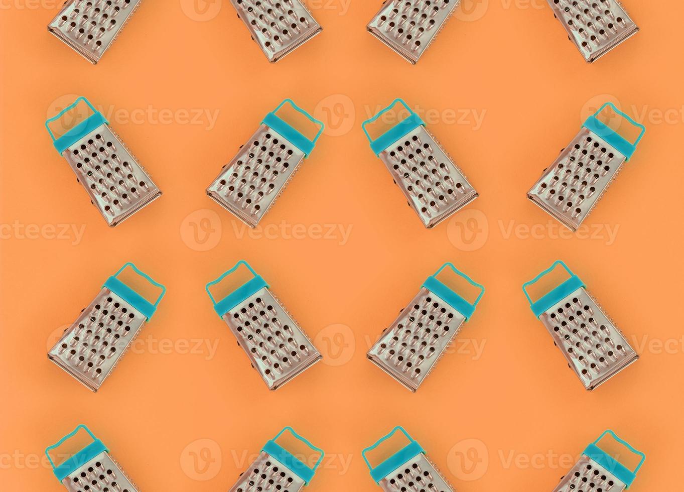 Small stainless steel graters lies on a pastel colored paper. Kitchen accessories. Tools for cooking. Flat lay top view photo