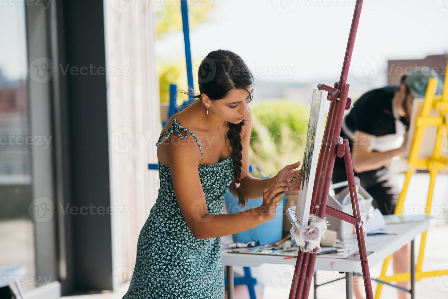 Young woman artist paints with a spatula on the canvas photo