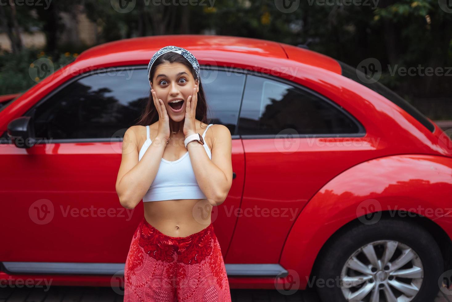 retrato de una mujer bastante caucásica parada contra un auto rojo nuevo foto