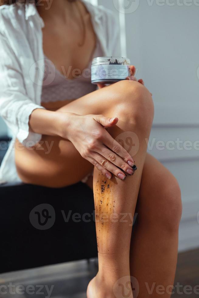 mujer joven aplicando exfoliante natural en su cuerpo, vista cercana foto