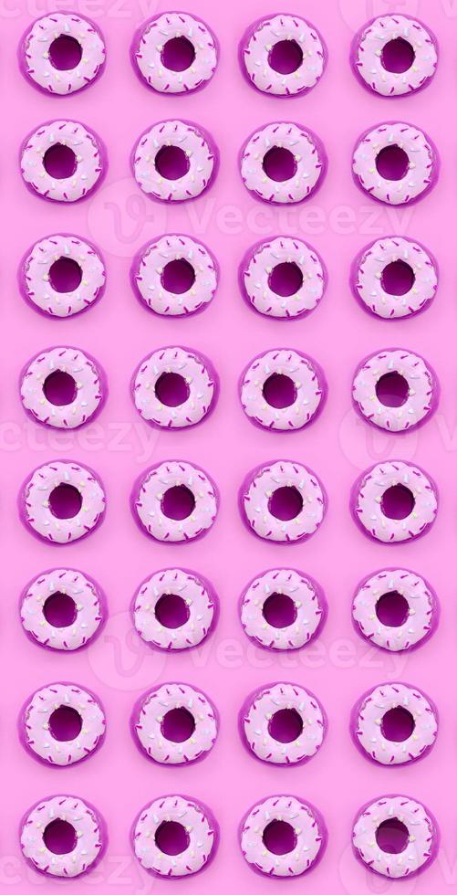 Many small plastic donuts lies on a pastel colorful background. Flat lay minimal pattern. Top view photo