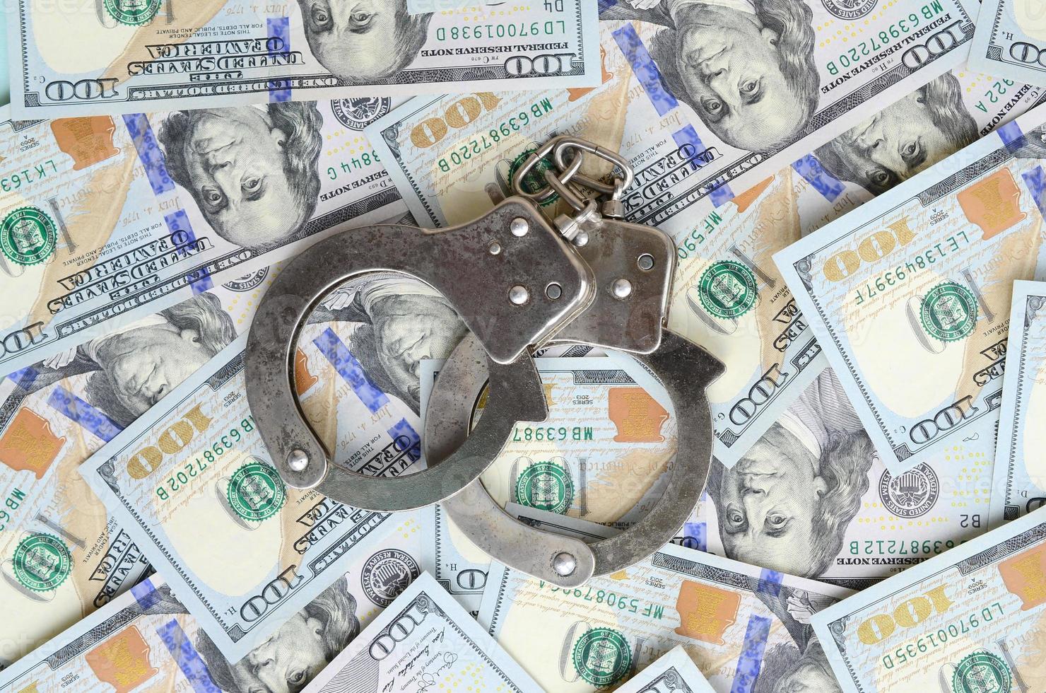 Silver police handcuffs lies on a many dollar bills photo