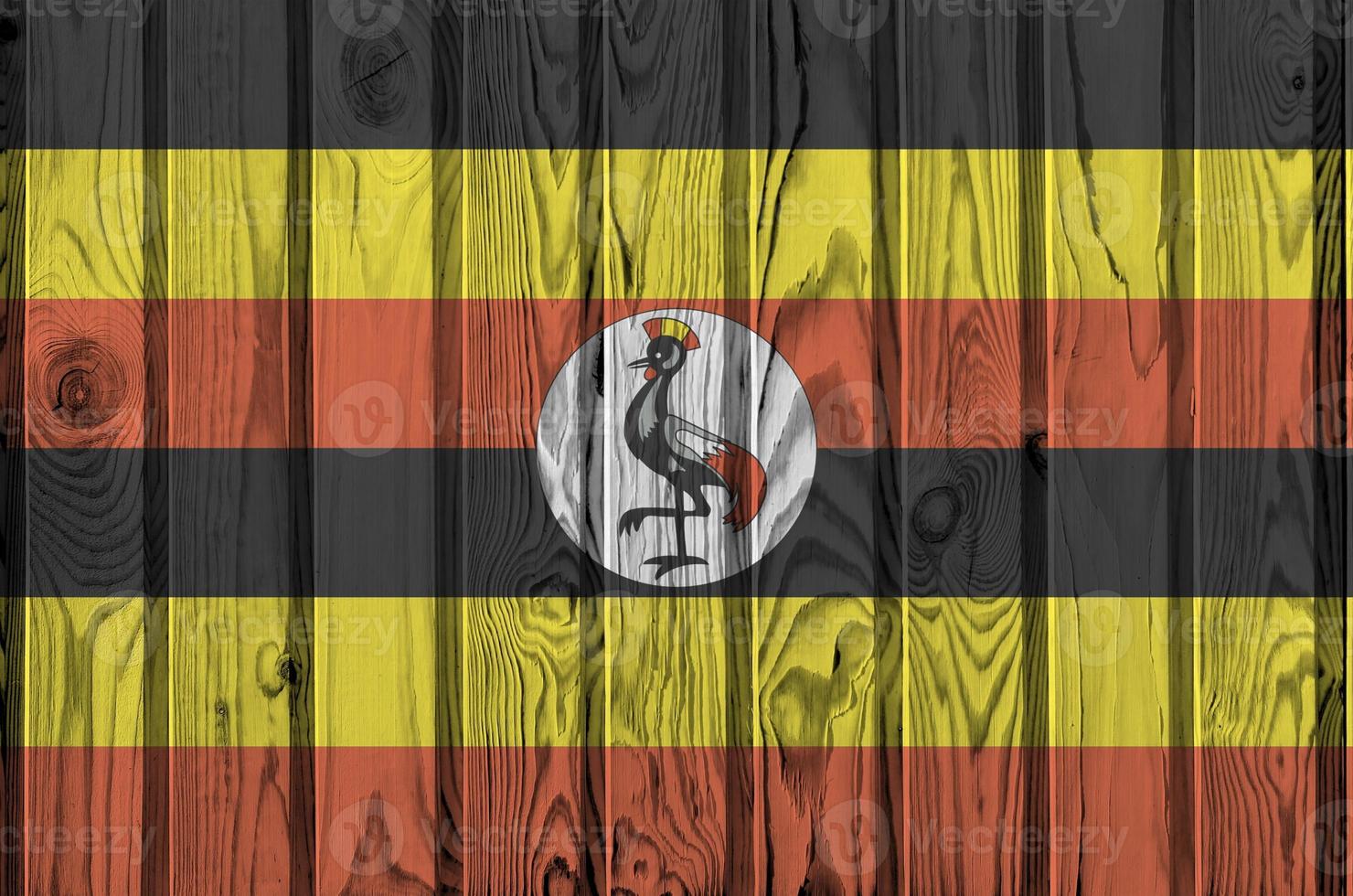 Uganda flag depicted in bright paint colors on old wooden wall. Textured banner on rough background photo