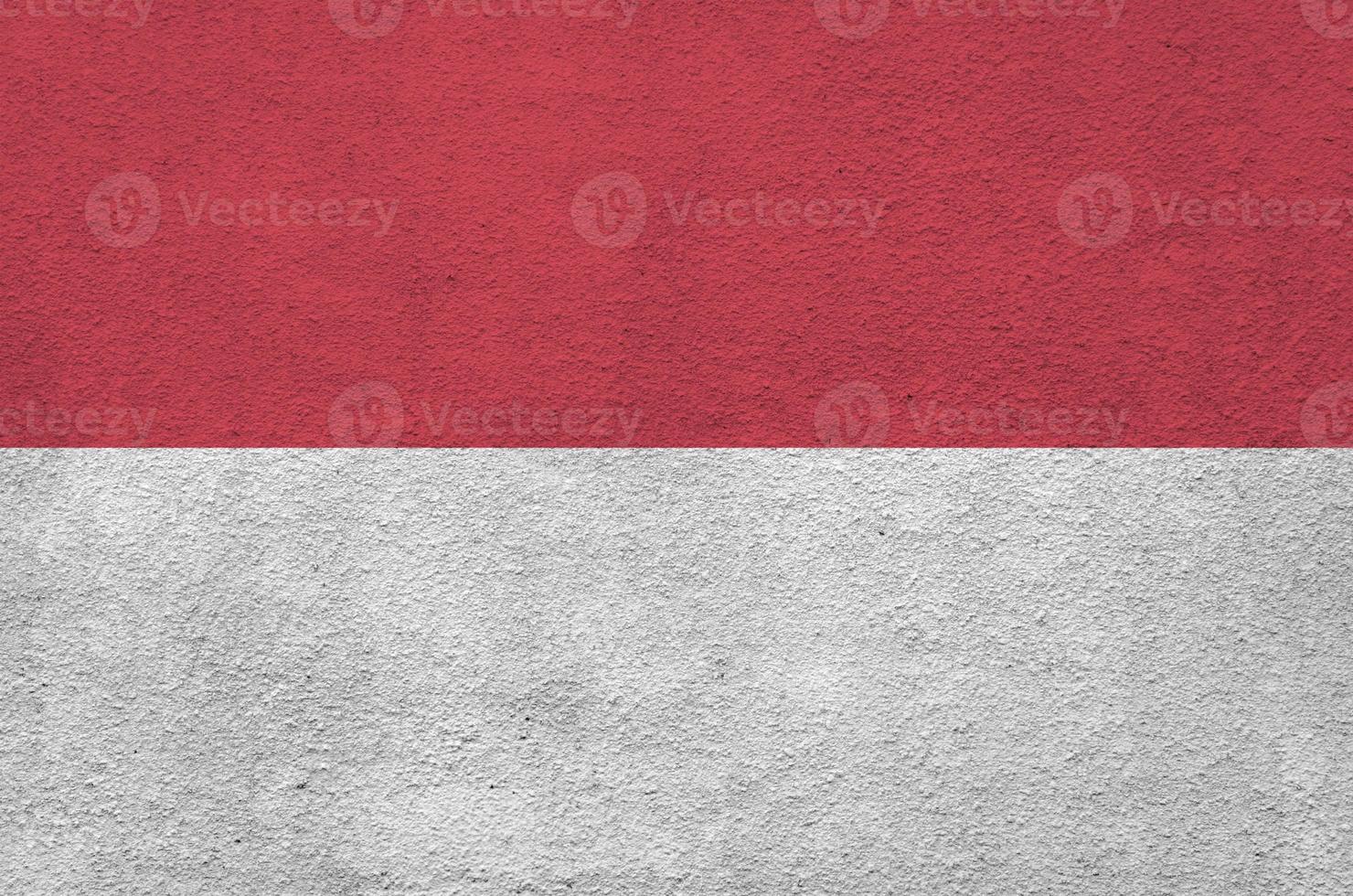 Indonesia flag depicted in bright paint colors on old relief plastering wall. Textured banner on rough background photo
