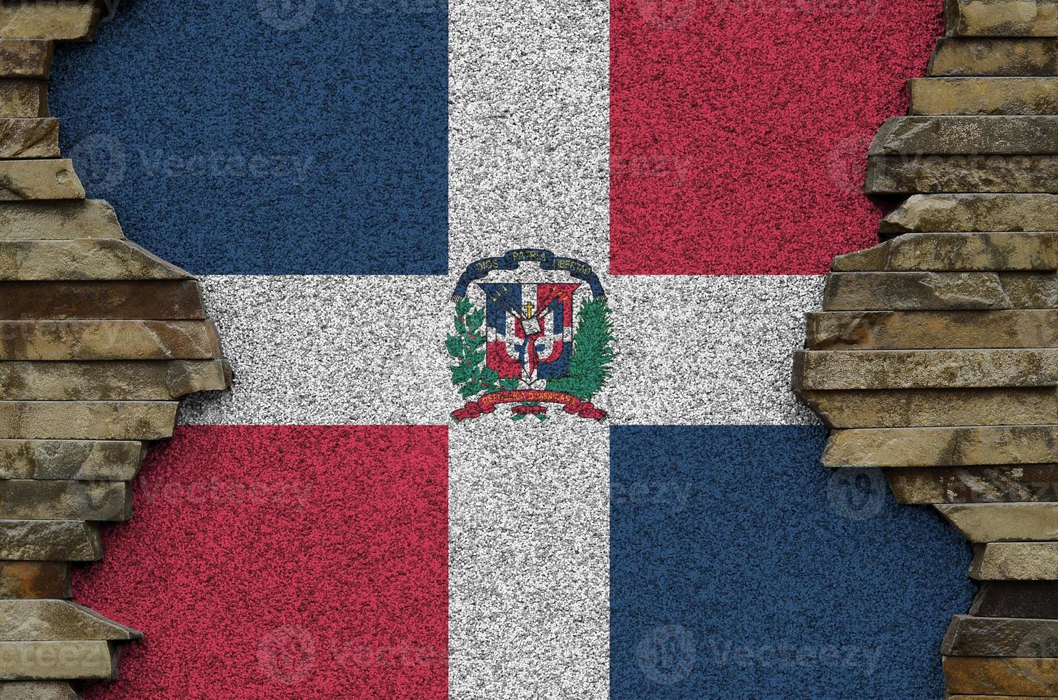 bandera de la república dominicana representada en colores de pintura en el primer plano de la pared de piedra antigua. banner texturizado sobre fondo de pared de roca foto