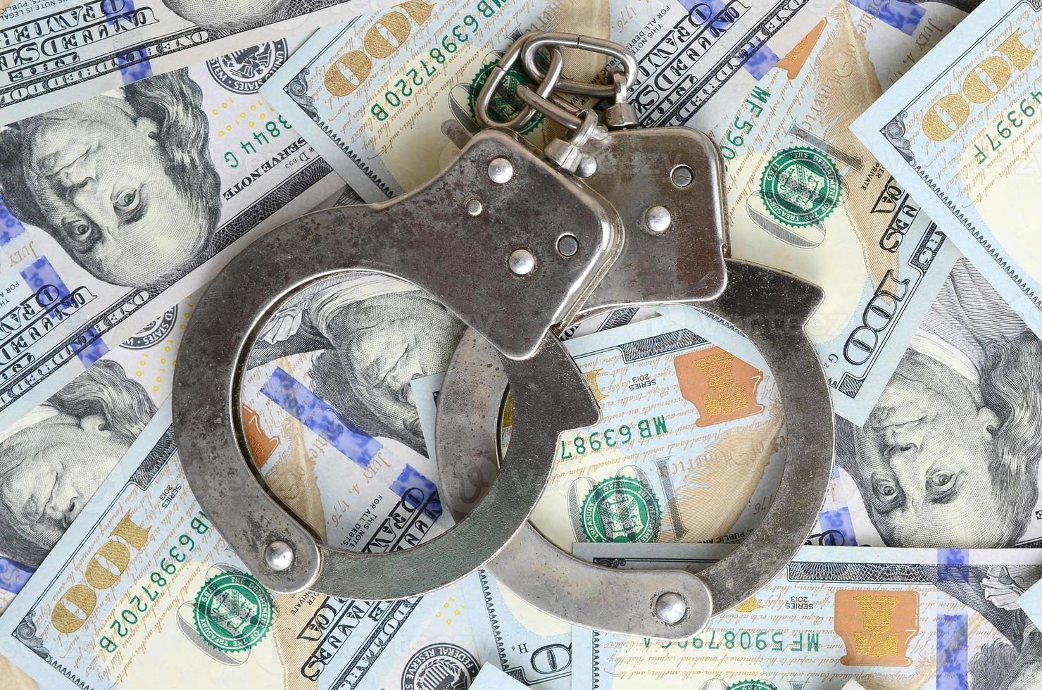 Silver police handcuffs lies on a many dollar bills photo