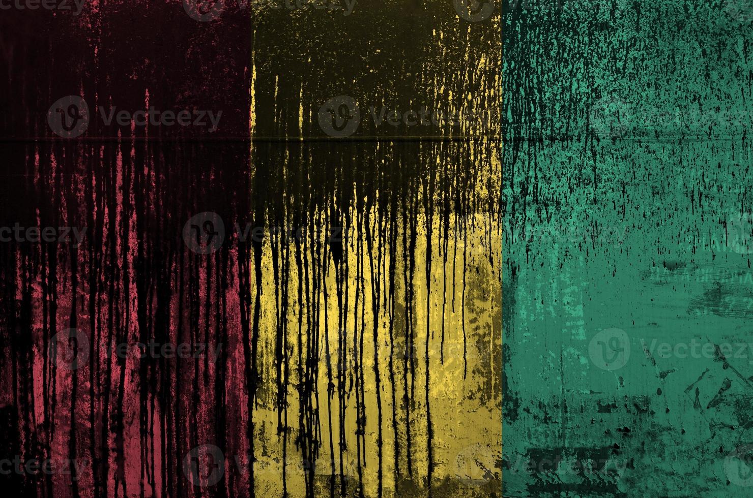 Guinea flag depicted in paint colors on old and dirty oil barrel wall closeup. Textured banner on rough background photo