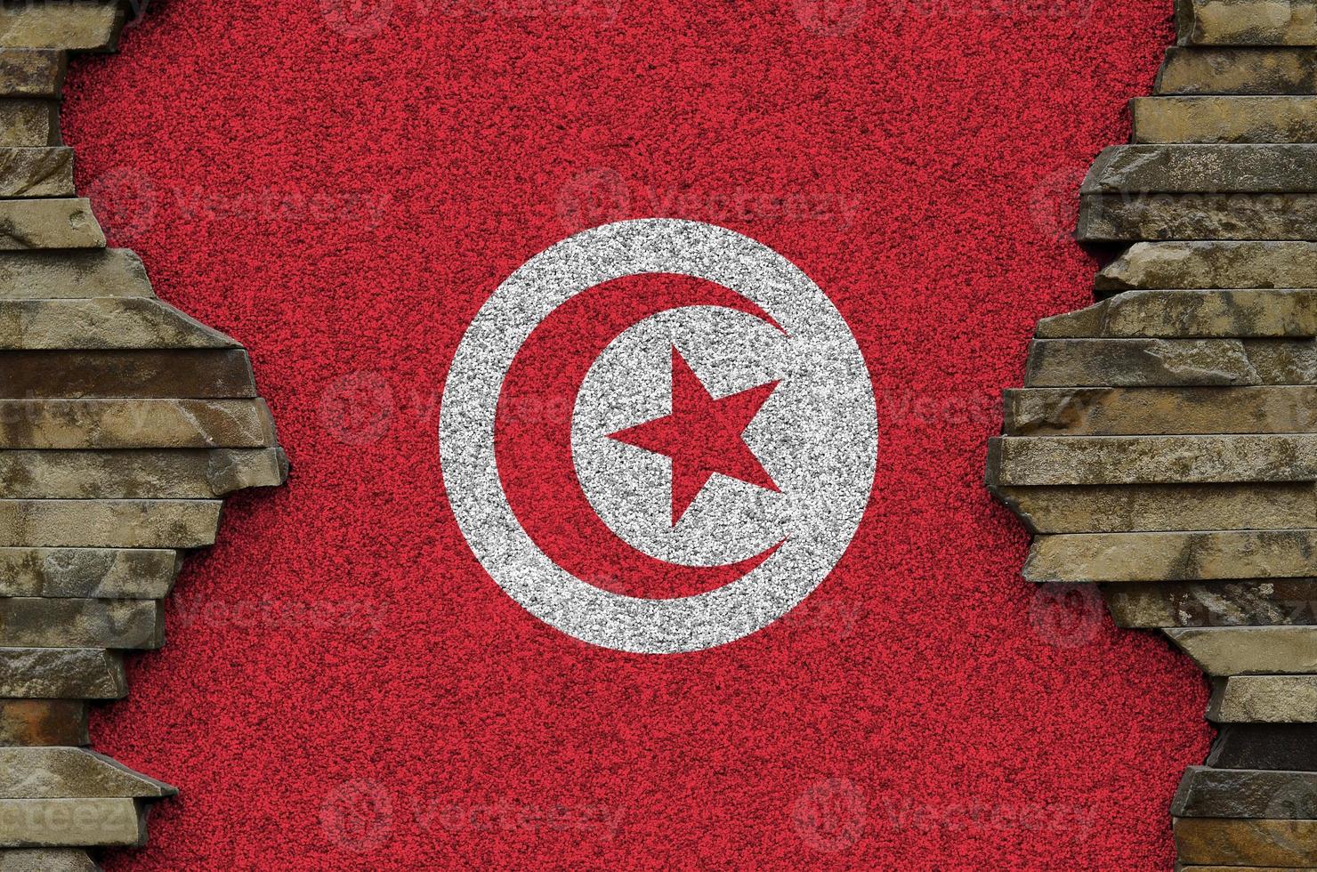 Tunisia flag depicted in paint colors on old stone wall closeup. Textured banner on rock wall background photo