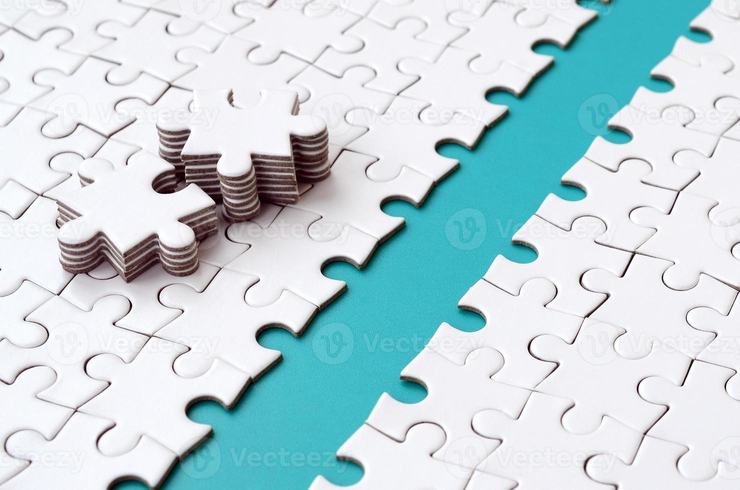 The blue path is laid on the platform of a white folded jigsaw puzzle. The missing elements of the puzzle are stacked nearby. Texture image with space for text photo