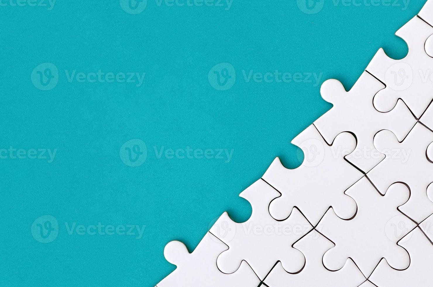Fragment of a folded white jigsaw puzzle on the background of a blue plastic surface. Texture photo with copy space for text