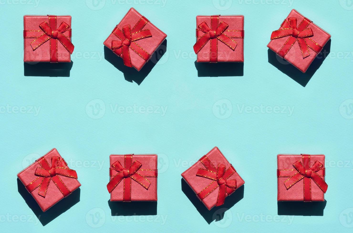 Many small red pink gift boxes on texture background of fashion trendy pastel blue color paper in minimal concept. Abstract pattern photo