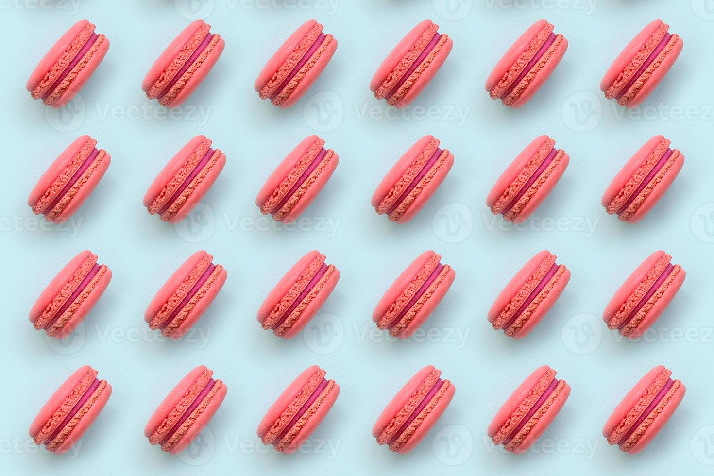 Pink dessert cake macaron or macaroon on trendy pastel blue background top view. Flat lay pattern composition photo