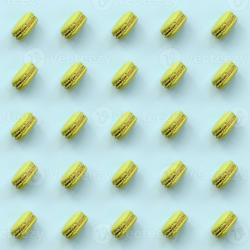 Green dessert cake macaron or macaroon on trendy pastel blue background top view. Flat lay pattern composition photo