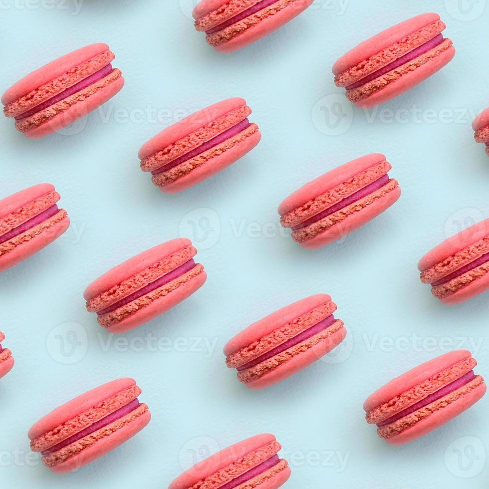 Pink dessert cake macaron or macaroon on trendy pastel blue background top view. Flat lay pattern composition photo