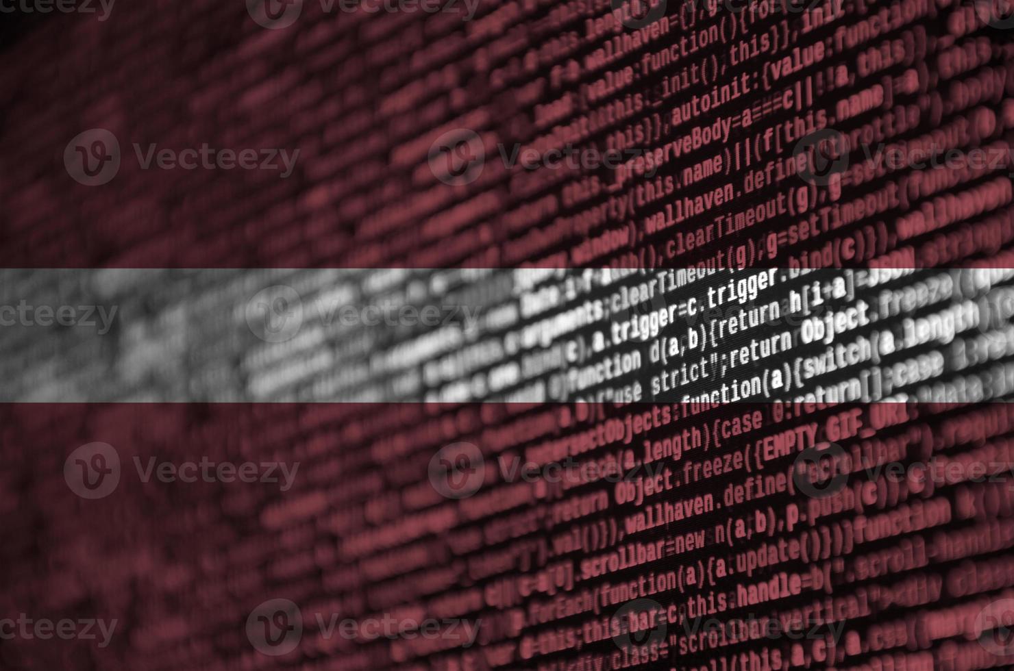 La bandera de Letonia se representa en la pantalla con el código del programa. el concepto de tecnología moderna y desarrollo de sitios foto