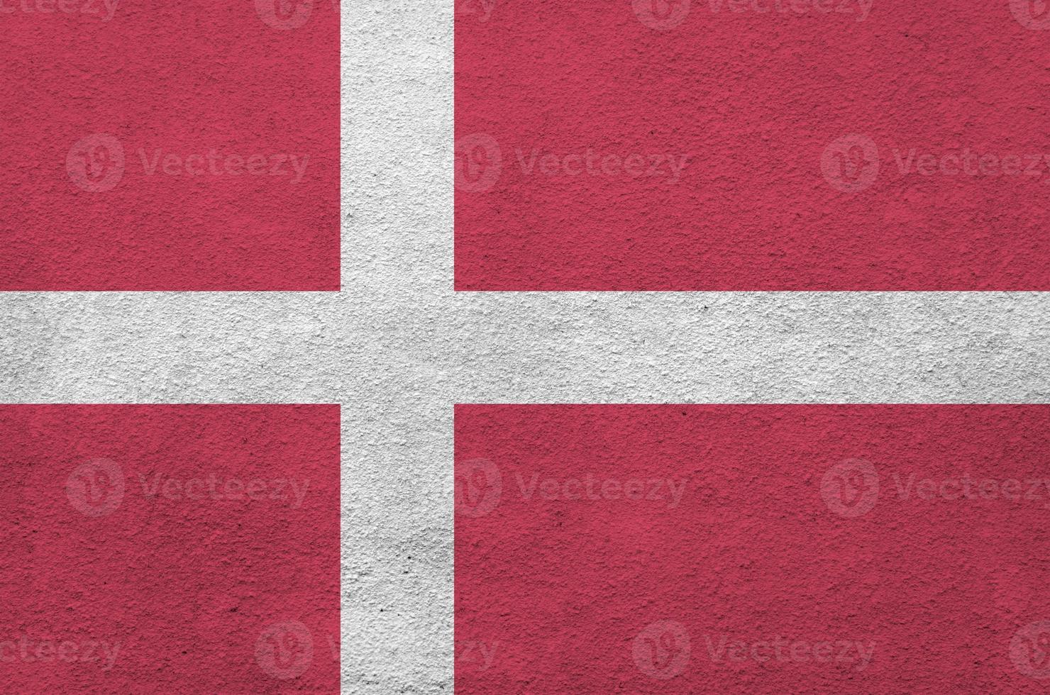 Denmark flag depicted in bright paint colors on old relief plastering wall. Textured banner on rough background photo