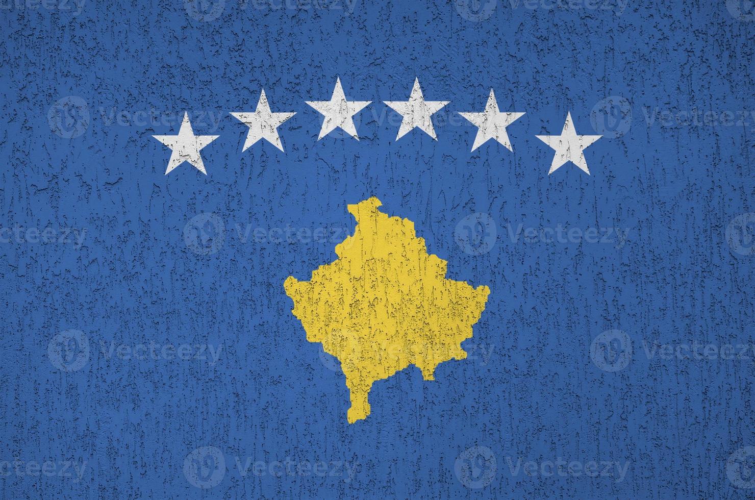 Kosovo flag depicted in bright paint colors on old relief plastering wall. Textured banner on rough background photo
