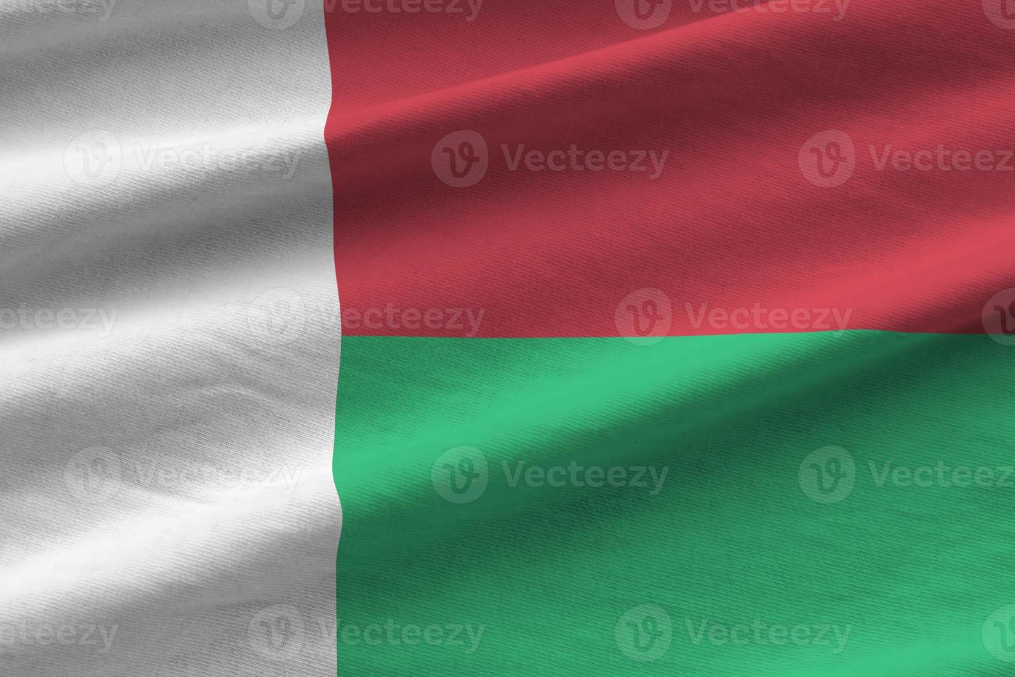 Madagascar flag with big folds waving close up under the studio light indoors. The official symbols and colors in banner photo